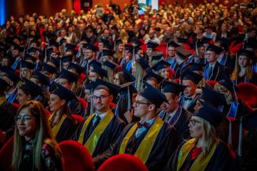 Viele Studentinnen und Studenten mit Schärpe und Sponsionshut im Hörsaal